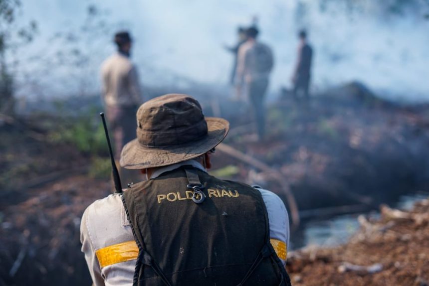 Petugas kepolisian saat memadamkan api di lokasi kebakaran lahan | source: Pemprov Riau