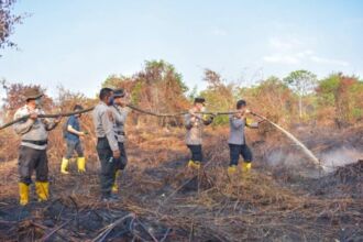 Petugas kepolisian bahu membahu melakukan pendinginan lahan pasca terbakar | Foto: dok. MC Riau