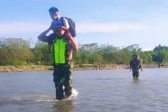 Setiap hari Babinsa selalu siaga dan siap membantu anak-anak menyeberangi sungai | Source: Dispenad