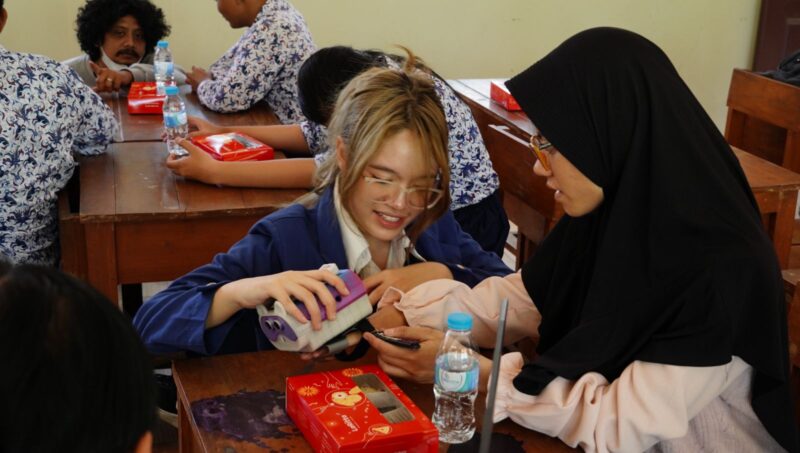 Salah satu anggota tim inovator ITS, Firania Putri Harsanti, mempraktikkan cara menggunakan Neutrack AI Glove pada salah satu siswa SMPLB-A YPAB Surabaya | Foto: Humas ITS