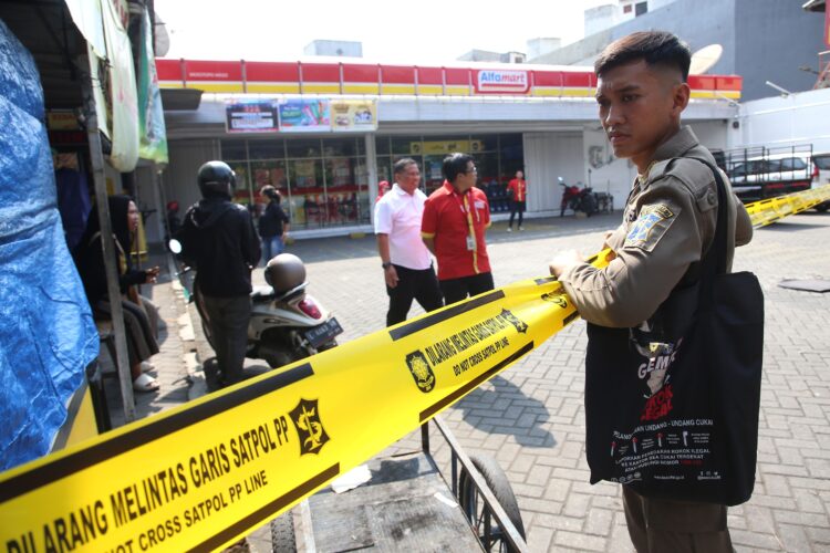 Petugas memasang garis Satpol PP Line terhadap salah satu toko modern di Surabaya, Selasa (10/6/2025) | Sumber Foto: Pemkot Surabaya