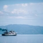 Ilustrasi: Kapal penyebrangan melintas di perairan dengan latar pegunungan | Sumber Foto: Pixabay