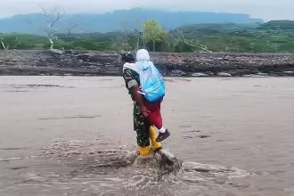 Serka Novi Wahyu Santoso saat menyebrangkan bocah SD melintasi sungai aliran lahar Gunung Semeru | Source: Infopublik